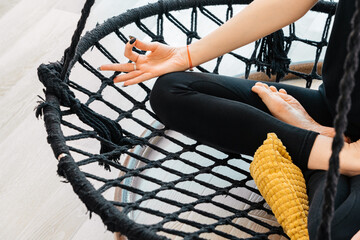 Close up of yoga girl sitting in lotus asana on hammock during yoga class, cropped view