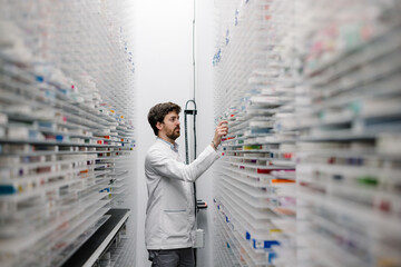 Pharmacist organizing medications in modern pharmacy storage room