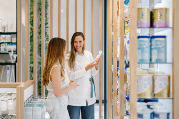 Pharmacist assisting customer with product choice in modern pharmacy