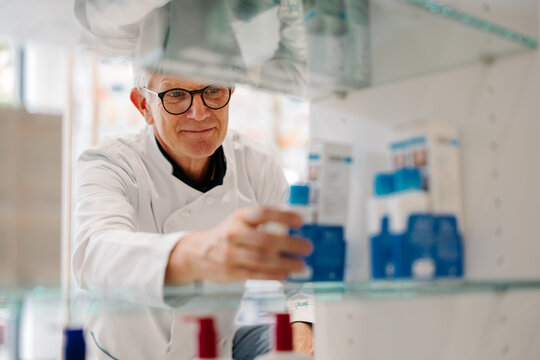 Pharmacist organizing medication on pharmacy shelves