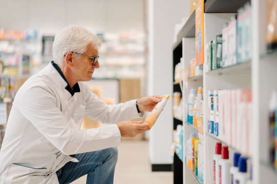 Pharmacist examining product on shelf in a modern pharmacy.