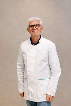 Mature pharmacist in white coat standing with confident smile