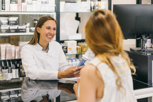 Pharmacist assisting customer in a modern pharmacy interior