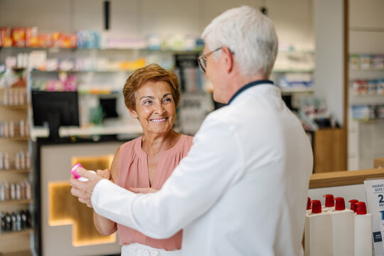 Pharmacist assisting smiling customer with medication in pharmacy