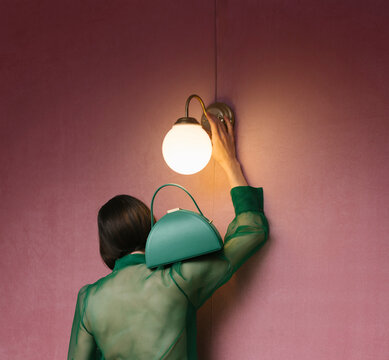 Woman in Green Blouse Adjusting Wall Lamp