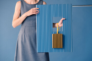 Woman Holding Shopping Bag Through Blue Cardboard Frame