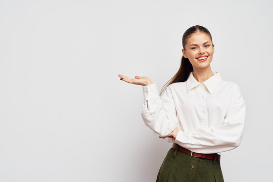 Smiling woman in a white shirt presenting on a neutral background, confident and approachable Stylish outfit exudes professionalism and friendliness, perfect for business contexts