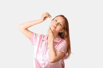 Fototapeta premium Pretty young woman with cosmetic oil on light background