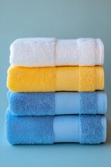 Colorful stacked towels in white, yellow, and blue against soft blue background