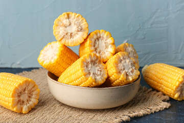 Bowl with cut fresh corn cobs on blue table
