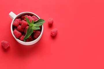 Cup with fresh raspberries and mint on red background