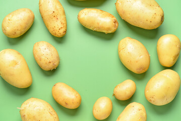 Frame made of raw potatoes on green background