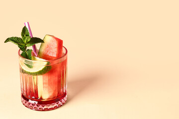 Glass of fresh watermelon lemonade with lime and mint on yellow table