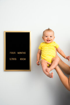 Four months old baby in her father's hand next to development chart