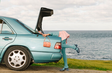 Woman Searching in Car Trunk by the Ocean