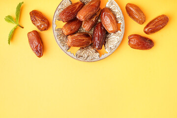 Bowl with dried dates on yellow background
