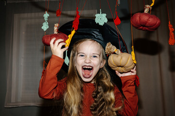 Girl with spooky face among halloween-themed decorations