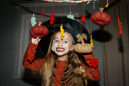 Excited child in witch hat with halloween decorations