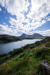 Fototapeta premium The image shows a body of water surrounded by hills in Loch a' Chàirn Bhàin, Scotland. The scene includes clouds, nature, water, sky, mountains, and a highland landscape.