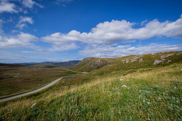 Generate Description
The image shows a grassy hill with a dirt road in Scotland. The landscape includes lush greenery and clouds in the sky.