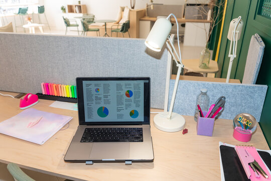 Laptop With Charts In An Organized Desk in Coworking Space Office - Powered by Adobe