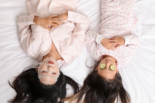 Asian mother with her little daughter relaxing on bed, top view - Powered by Adobe