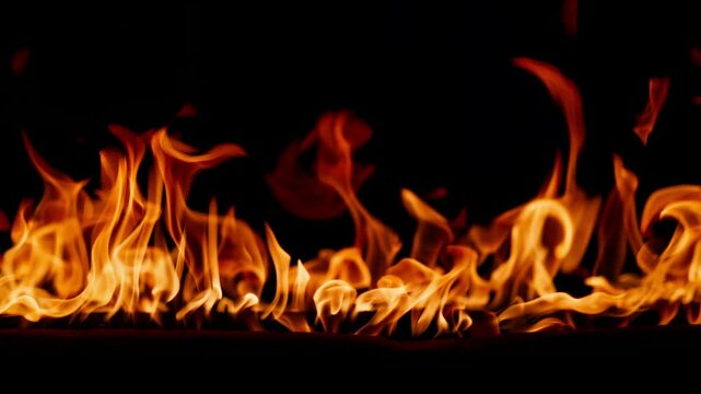Beautiful dancing fire, the surface is ablaze. Close-up immersion in the flames. The camera passes through the fire. Burning tongues of flame on a black backdrop in slow motion.