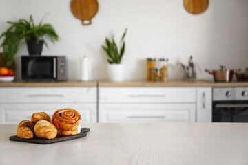 Wooden board with different pastry on table in modern kitchen