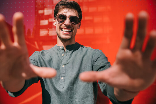 Happy man in sunglasses against vibrant red background, Azca Madrid