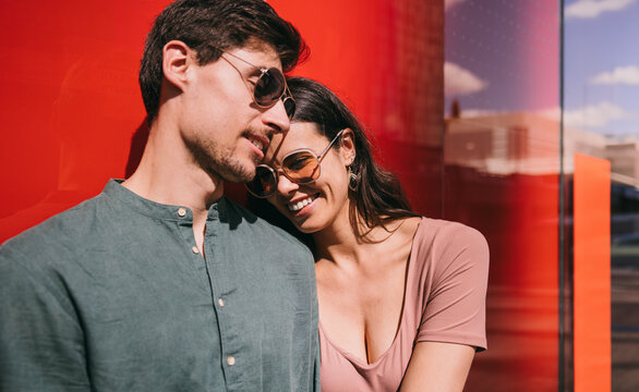 Affectionate couple enjoying sunny day against a red wall