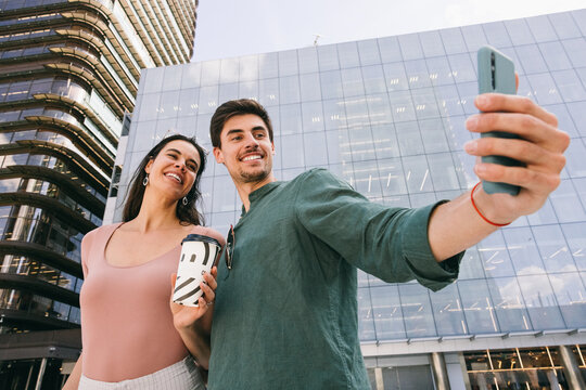 Happy couple taking a selfie in Azca, Madrid, with modern buildings