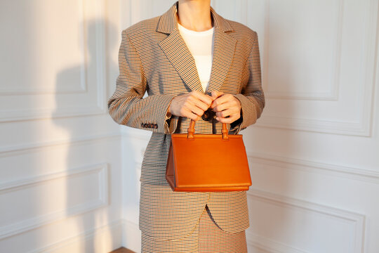 Woman in Elegant Blazer Holding Stylish Brown Handbag
