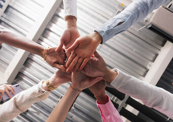 Multiracial people stacking hands.