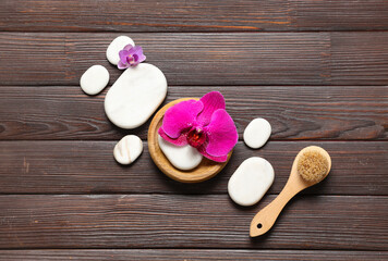 Spa stones, brush and orchid flowers on wooden background