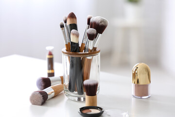 Makeup brushes with eyeshadows and lipstick on white table at home