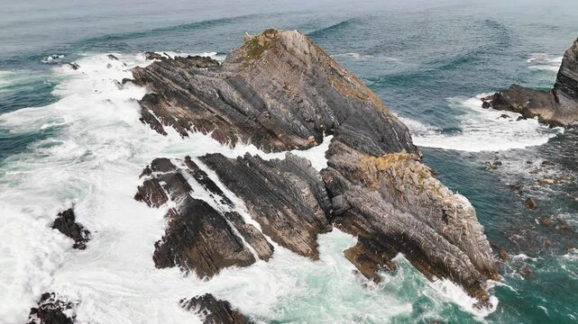 Flying around giant rock washed by the huge ocean waves. Arrifana, Atlantic western coast, Portugal