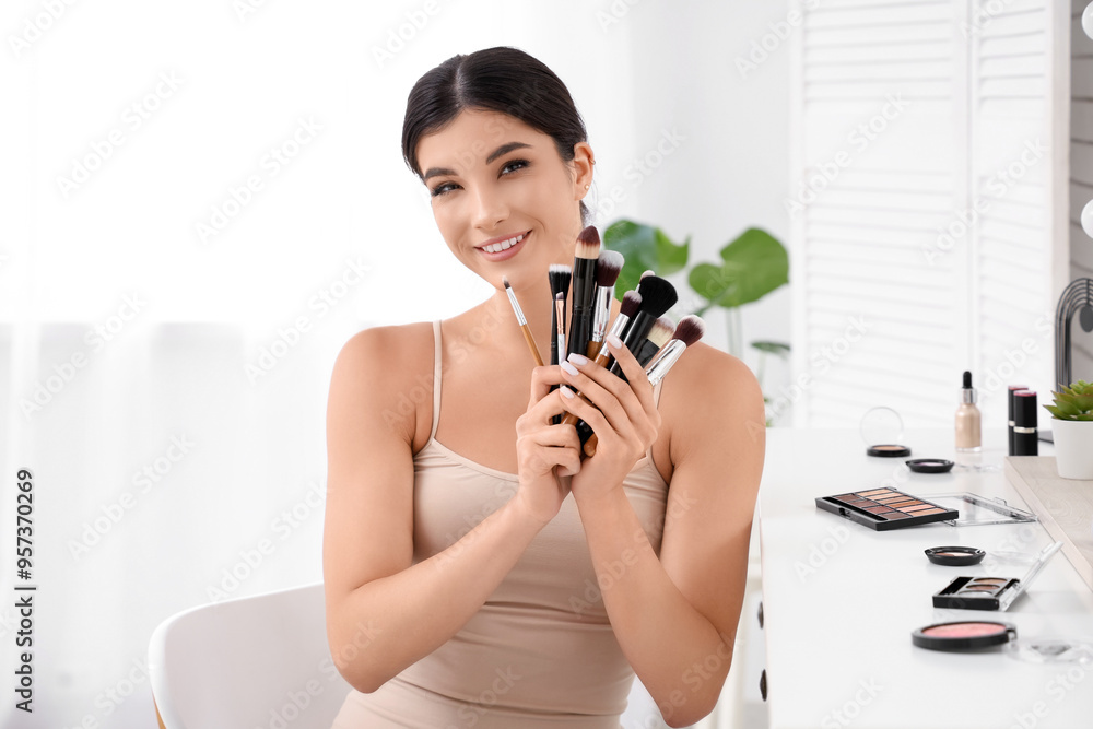 Wall mural Beautiful young woman with makeup brushes in salon