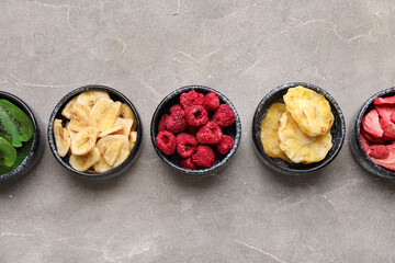 Bowls of different dehydrated fruits and berries on grey background