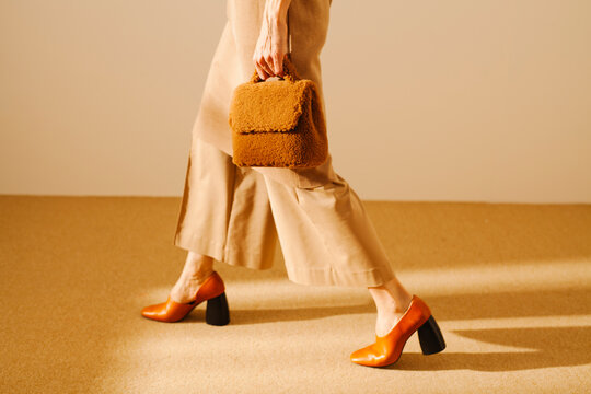 Stylish Woman Walking in Beige Outfit with Brown Handbag