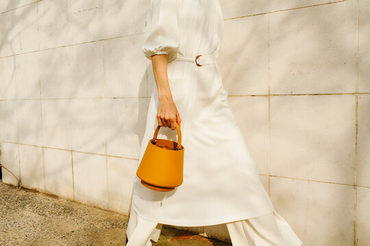 Fashionable Woman Holding Orange Handbag and Walking