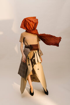Fashion Model In Avant-Garde Outfit With Red Scarf And Beige Coa