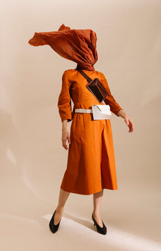 Fashion Model In Artistic Orange Dress With Fabric Wrapped Head