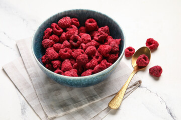 Bowl of dehydrated raspberries on white background