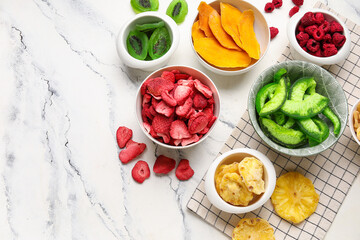 Bowls of different dehydrated fruits and berries on white background