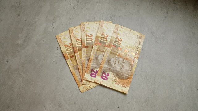 South african twenty rand banknotes displayed on a concrete surface featuring nelson mandela's portrait, showcasing south african currency in a plain setting.