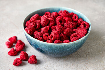 Bowl of dehydrated raspberries on grey background