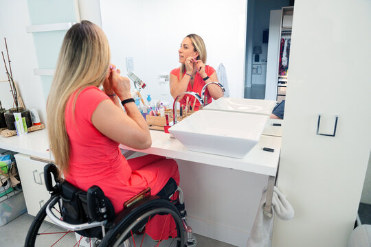 Person in wheelchair applying makeup at bathroom vanity