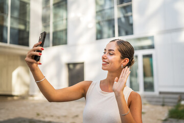 Young woman stand in front building have video call on mobile phone