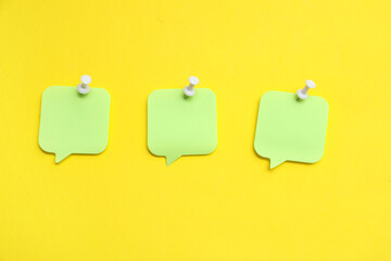 Paper notes in shape of speech bubble pinned on yellow background