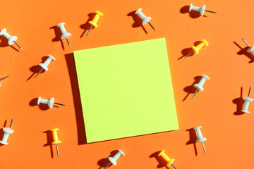 Paper note with pins on orange background